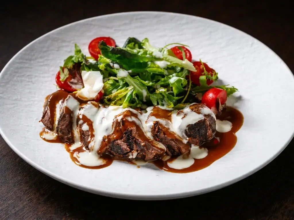 Tagliata servită cu cartofi ca acasă, mix de salată și sos de parmezan